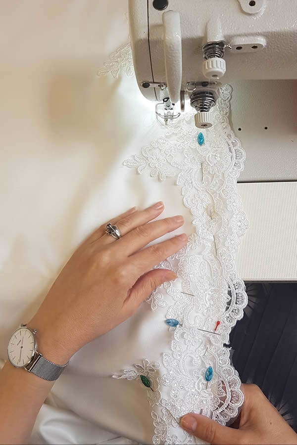 Stitching lace trim on a wedding dress.